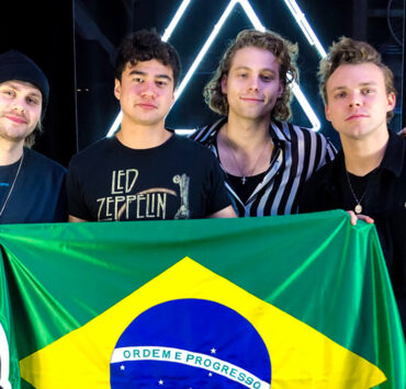 Integrantes do 5 Seconds of Summer segurando a bandeira do Brasil