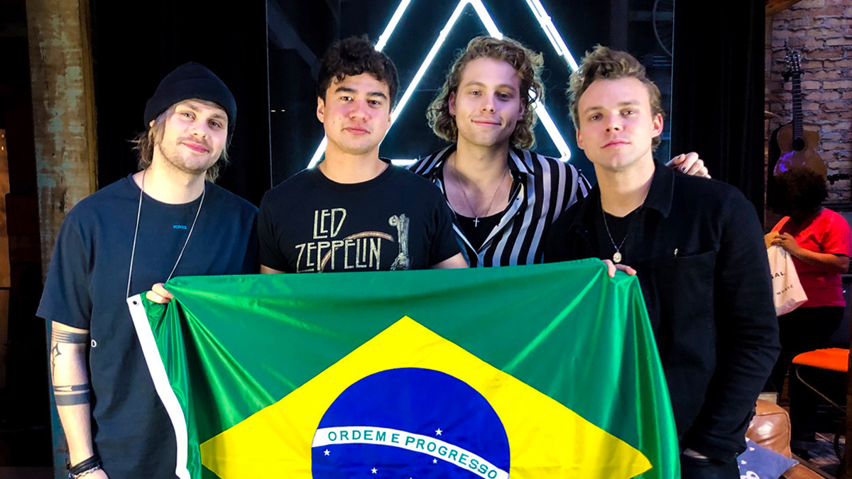 Integrantes do 5 Seconds of Summer segurando a bandeira do Brasil